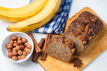 Healthy sugar free whole wheat banana bread with nuts and cinnamon cut into slices on a wooden serving board