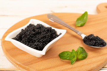 Bowl with black caviar on on wooden table