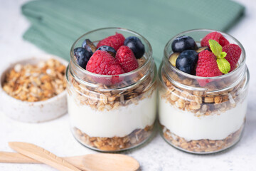 Greek yogurt parfait with granola and fresh berries in a jar, closeup view