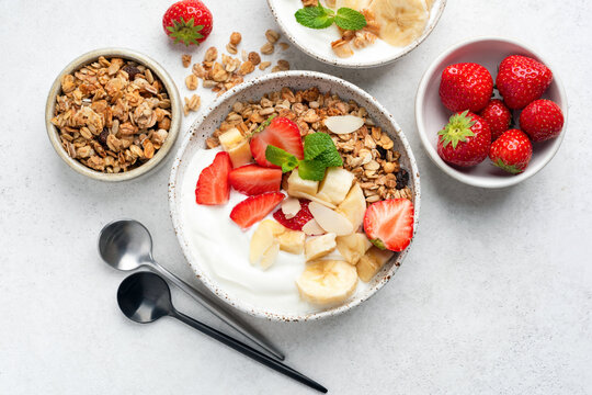 Greek yogurt bowl with banana, strawberry and granola. Table top view