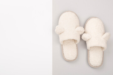Soft teddy slippers on color background, top view