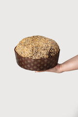 A woman hand holding a soft, golden panettone filled with chocolate cream, offering a delightful twist on the classic Italian holiday cake, set against a simple white background.
