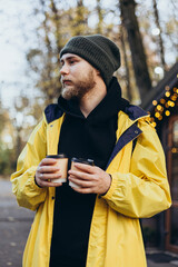 Stylish young man with paper cups near coffee shop outside.