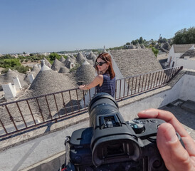 A woman poses in front of a white trulli in Apulia.