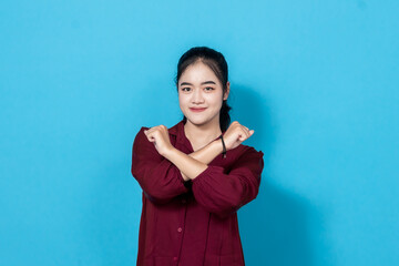 Portrait of a confident young woman wearing a red shirt, gesturing stop posing against a blue...