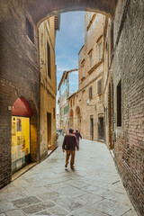 Fototapeta premium Old street in the historical center of Siena, the UNESCO World Heritage Centre unchanged for 13-14 centuries, with its medieval streets looked like in the early Middle Ages. Italy, 2019 