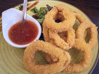 fried calamari rings on wooden cutting board served with red sauce