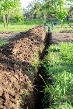 Carrying out drip irrigation in the garden. A ditch dug in the ground for laying the irrigation pipe
