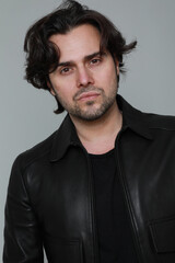 Obraz premium Bearded and handsome man wearing black jacket and looking at the camera. Vertical.