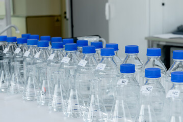 Laboratory equipment. Laboratory storage bottles with blue polypropylene cap on white table.