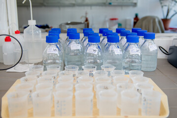 Laboratory equipment. Laboratory storage bottles with blue polypropylene cap on white table.