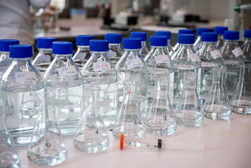 Laboratory equipment. Laboratory storage bottles with blue polypropylene cap on white table.