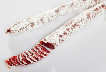 Spanish fuet sausages cut in slices on a white surface, close-up