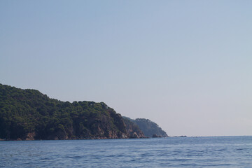Fototapeta premium Serene Coastal View with Rocky Shoreline and Lush Hills