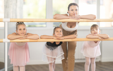 Children and female teacher pose at ballet stand bare. Report shot with children and mentor for...