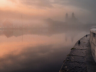River Shannon in a fog at warm sunset, Church of Saints Peter and Paul in the background and...