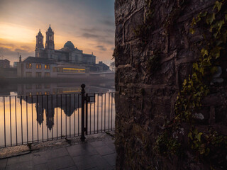 View on Church of Saints Peter and Paul at dusk. Warm color light. Cloudy sky reflects in river...