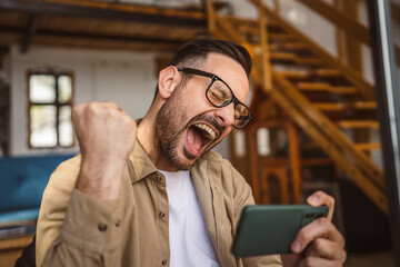 Adult man with eyeglasses play video games on his phone at home