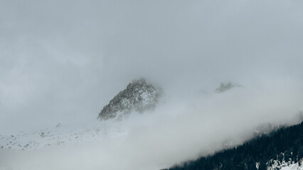 Low Clouds Are Swirling Around Snow-Capped Mountain Peaks In A Winter Scene. French Alps, Col de Balme