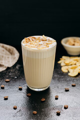 Creamy latte with whipped foam, dried apple slices, and cinnamon, served on a dark textured surface