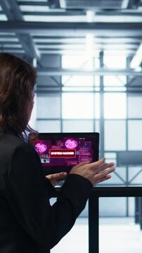Vertical video Data center engineers struggling to contain virus infestation, working on securing servers. Team of server farm employees detecting hacker attacks on tablet, fighting back, camera B