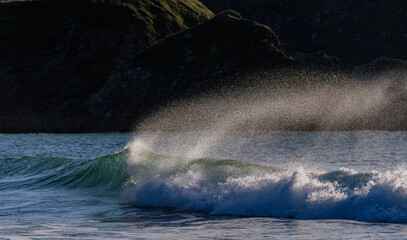 Fototapeta premium Écoussures d'une vague au bord de la mer près d'une côte rocheuse