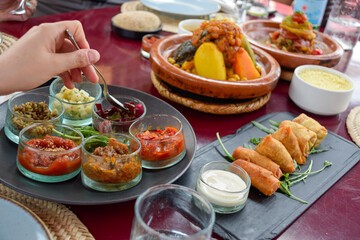 Hand serving food in table with Moroccan cuisine dishes as cous cous and tajin