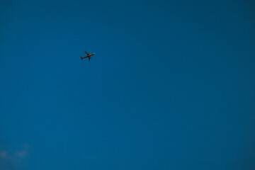 Fototapeta premium Silhouette of a plane flying in the blue sky.