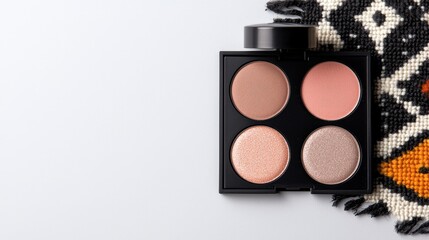 Makeup eyeshadow palette on white surface with patterned fabric