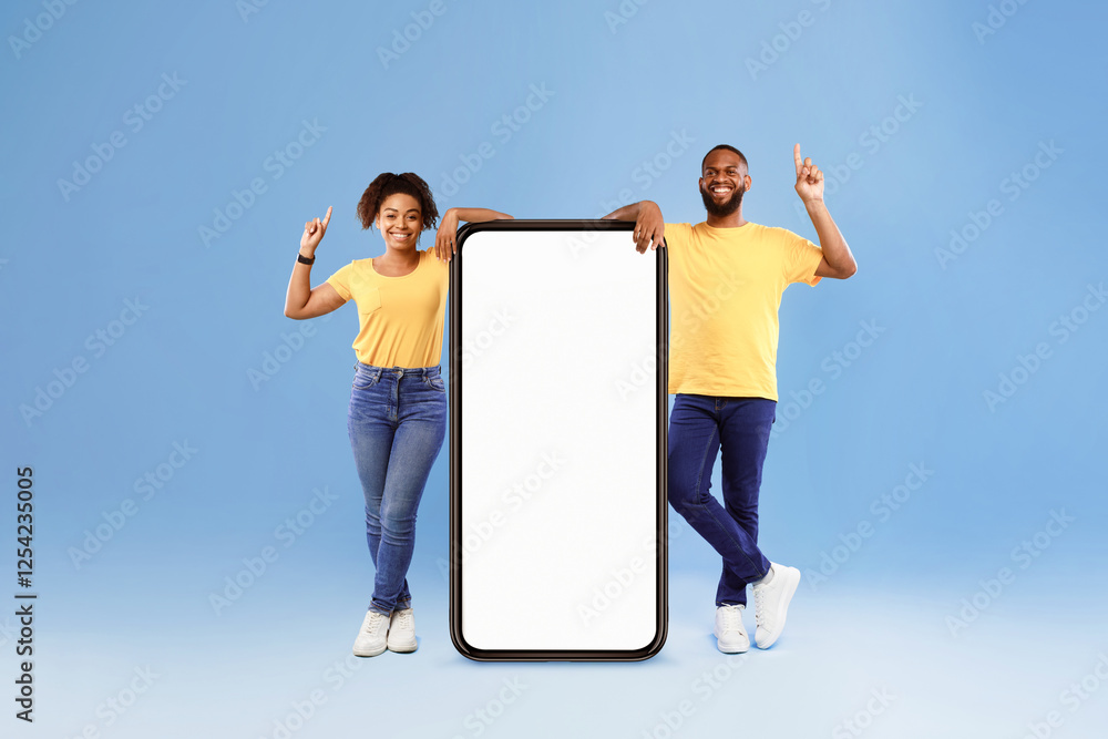 Poster positive african american couple demonstrating huge smartphone, offering mockup for your app or webs