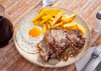 Austrian food: fried potatoes with meat, ham and egg in plate close-up