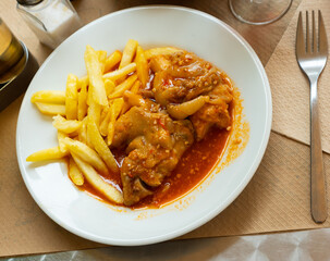 Pig's trotter served on white circular plate with fried potato.