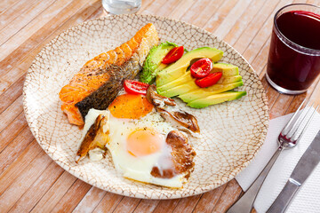 Delicious salmon fillet with avocado and scrambled eggs closeup