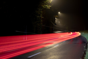Long exposure of red car light trails on a winding road at night