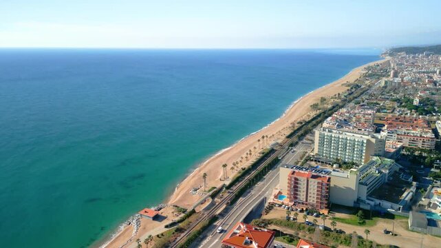 Mediterranean coastline with sandy beach and coastal buildings in pineda de mar, maresme region near barcelona, featuring turquoise waters and urban landscape