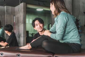 柔道整復師に足首の捻挫・ケガのリハビリを相談をするアジア人女性
