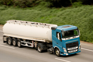 Blue Cabin Road Fuel Tanker Truck Driving on Highway with Cargo Tank