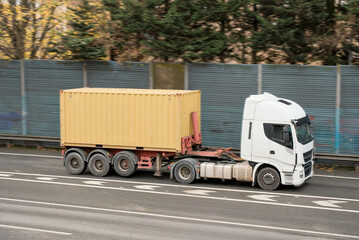White Truck Hauling Yellow ISO Standard Shipping Container on Highway
