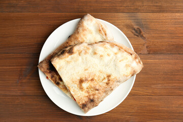 Halves of tasty calzone on wooden table, top view