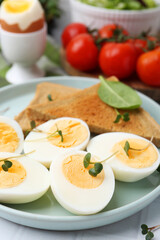 Cut hard boiled eggs with bread on white tiled table, closeup
