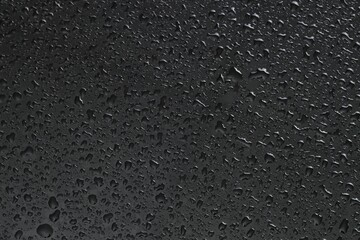 Water drops on dark grey glass surface, top view