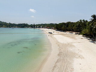 White sandy shoreline with lush palm trees and clear turquoise water. Haad Rin. Ko Pha Ngan, Thailand.