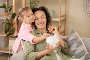 Little girl with her mother and piggy bank at home