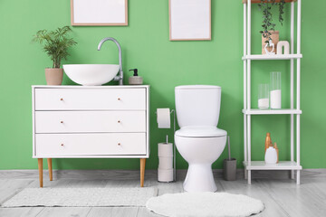 Interior of restroom with toilet bowl, sink and shelf unit