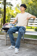 Obraz premium A young person relaxing on a park bench, enjoying a beautiful sunny day, perfect for themes like relaxation, outdoor leisure, and peaceful moments.