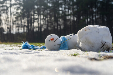 Melting snowman on a green grassy field. End of winter, hello spring. Winter and spring seasons...