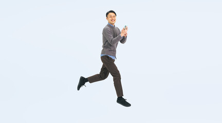 Fototapeta premium スマホを持ってジャンプするカジュアルウェアのミドル男性の全身写真（切り抜き背景透過PNGも販売しております。作成者リンクから「PNG」で検索してください）