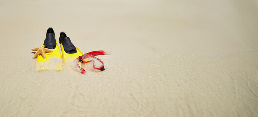 Yellow flippers, snorkel set and starfish on the beach