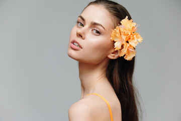 Fototapeta premium Elegant young woman with flower in hair, showcasing beauty and confidence, perfect for fashion and beauty concepts in spring.
