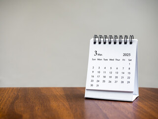 March 2025 page of desk calendar for organizer to plan and reminder, standing on wood table on...
